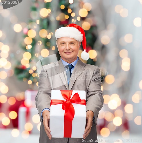 Image of smiling man in suit and santa helper hat with gift