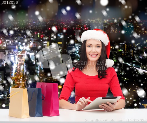 Image of smiling woman with shopping bags and tablet pc