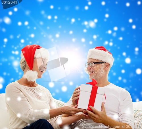 Image of happy senior couple with gift box at home
