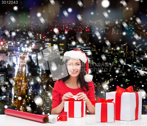 Image of smiling woman in santa helper hats packing gifts