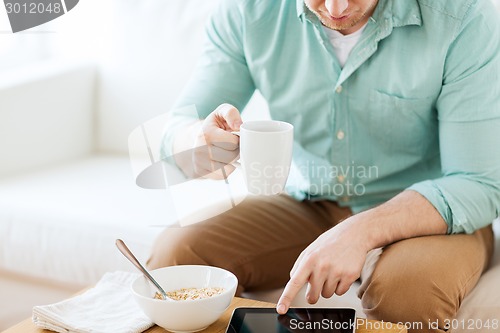 Image of close up of man with tablet pc having breakfast