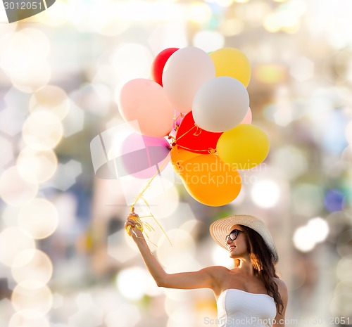 Image of smiling young woman in sunglasses with balloons