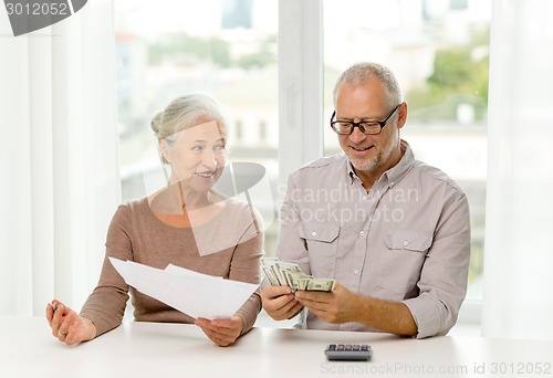 Image of senior couple with money and calculator at home