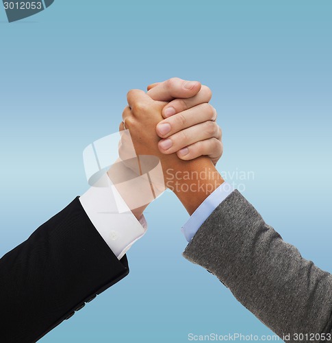 Image of close up of two hands multiracial armwrestling
