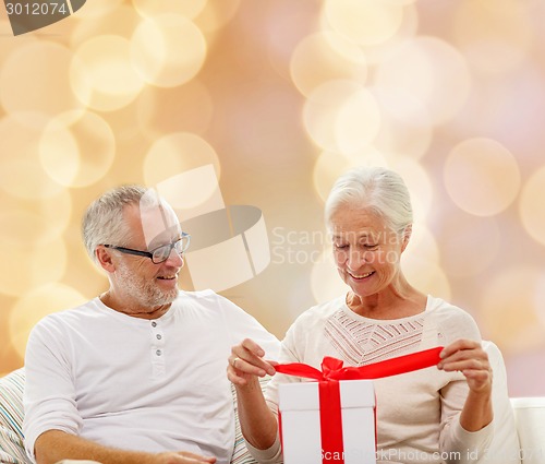 Image of happy senior couple with gift box at home