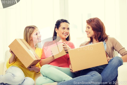 Image of smiling teenage girls with cardboard boxes at home