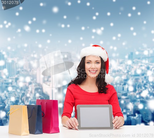 Image of smiling woman with shopping bags and tablet pc