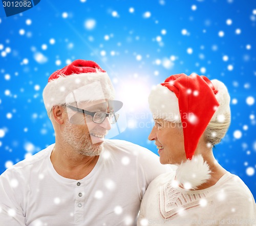 Image of happy senior couple in santa helper hats