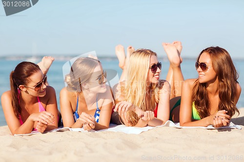 Image of group of smiling women in sunglasses on beach