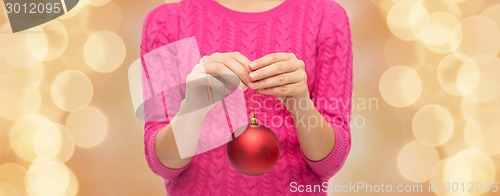 Image of close up of woman in sweater with christmas ball