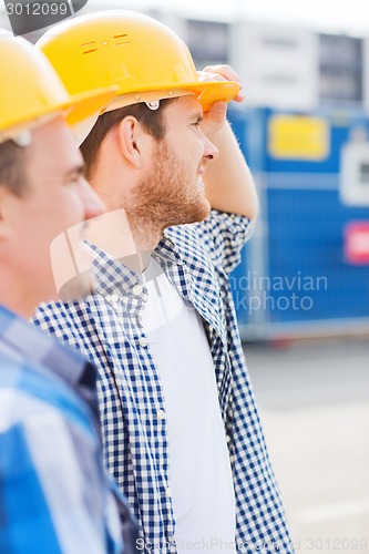 Image of group of smiling builders in hardhats outdoors