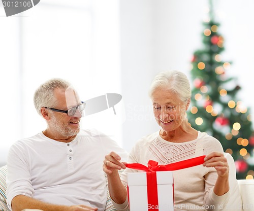 Image of happy senior couple with gift box at home