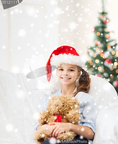 Image of smiling girl in santa helper hat with teddy bear