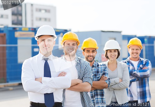 Image of group of smiling builders in hardhats outdoors