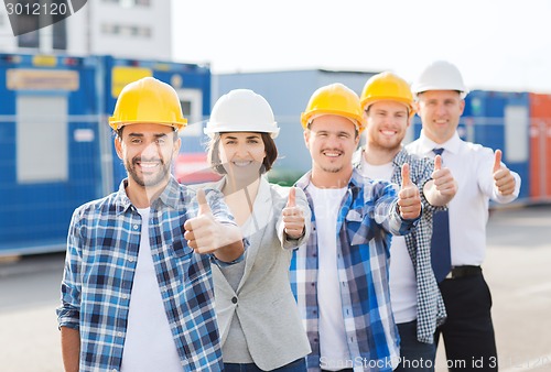 Image of group of smiling builders in hardhats outdoors