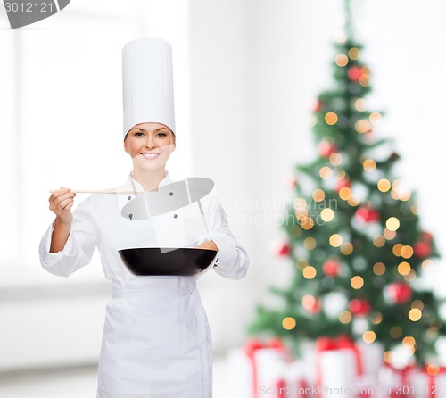 Image of smiling female chef with pan and spoon