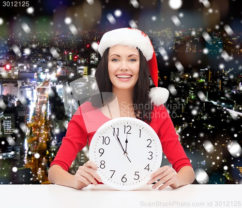 Image of smiling woman in santa helper hat with clock