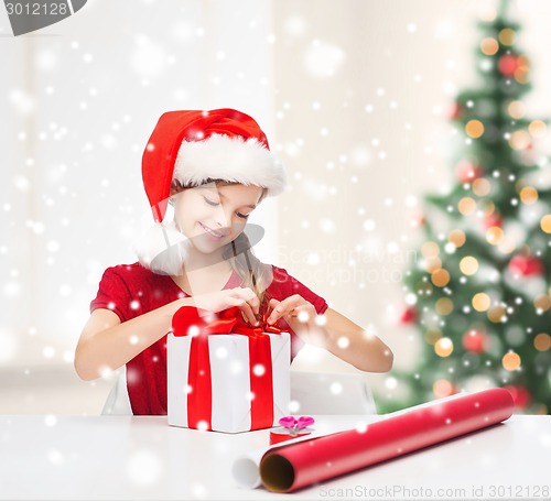 Image of smiling girl in santa helper hat with gift box