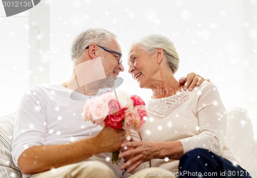 Image of happy senior couple with bunch of flowers at home