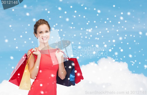 Image of smiling elegant woman in dress with shopping bags