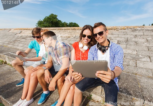 Image of group of smiling friends with tablet pc outdoors