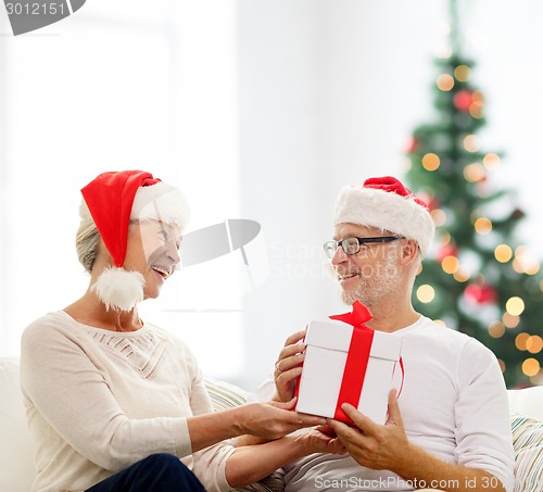 Image of happy senior couple with gift box at home