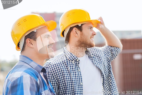 Image of group of smiling builders in hardhats outdoors