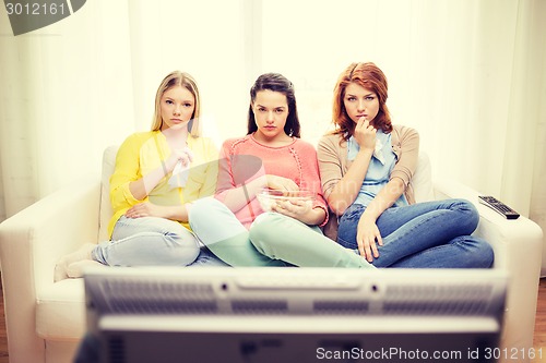 Image of three sad teenage girl watching tv at home