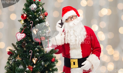 Image of santa claus with smartphone and christmas tree