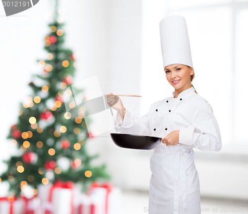 Image of smiling female chef with pan and spoon