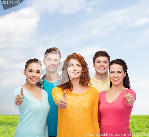 Image of group of smiling teenagers over blue sky and grass