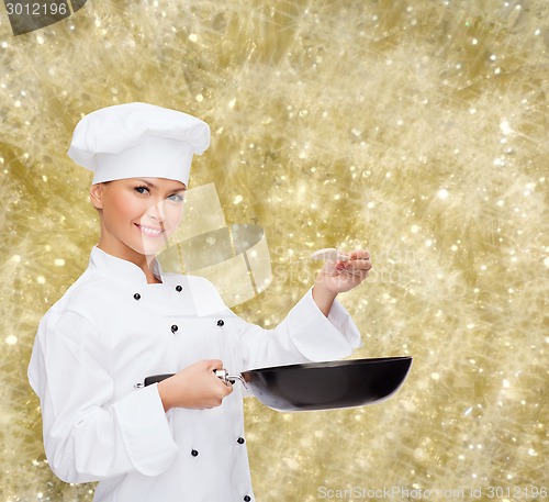 Image of smiling female chef with pan and spoon