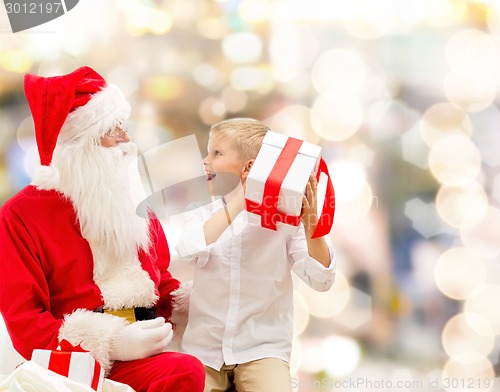 Image of smiling little boy with santa claus and gifts