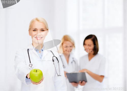 Image of smiling female doctor with green apple