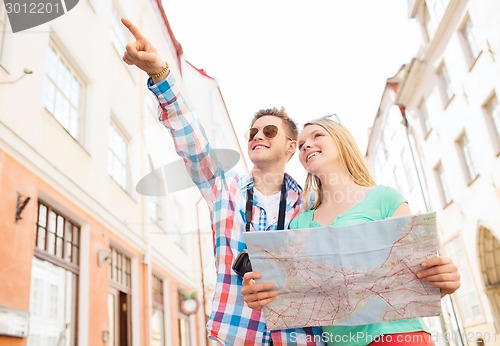 Image of smiling couple with map and photo camera in city