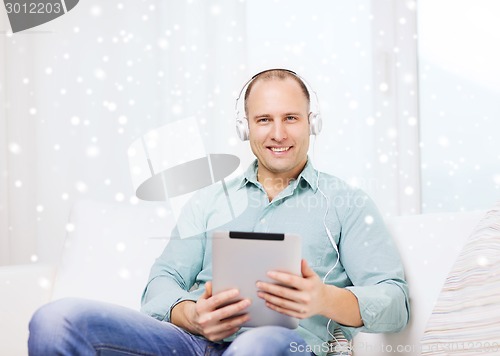 Image of smiling man with tablet pc sitting on couch