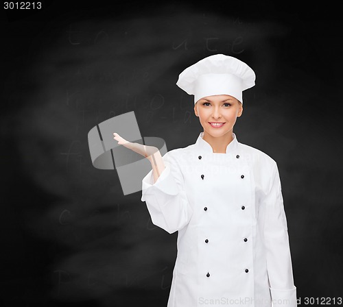 Image of smiling female chef holding something on hand