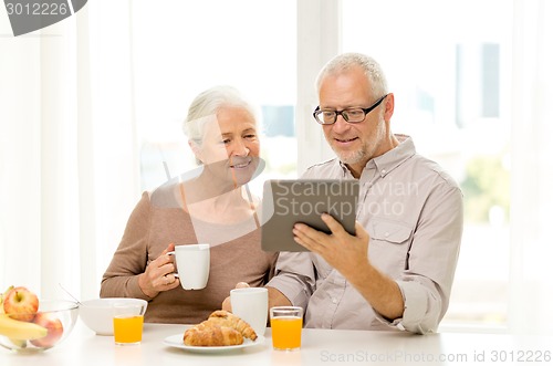 Image of happy senior couple with tablet pc at home