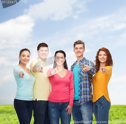 Image of group of smiling teenagers over blue sky and grass