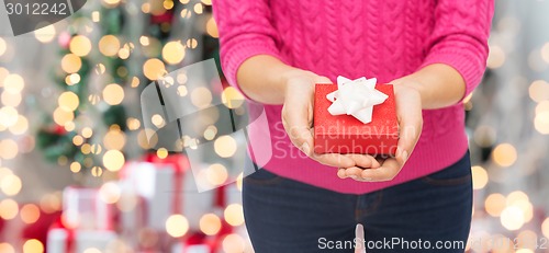 Image of close up of woman in pink sweater holding gift box