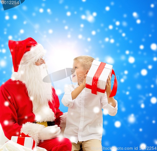 Image of smiling little boy with santa claus and gifts