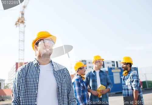 Image of group of smiling builders in hardhats outdoors