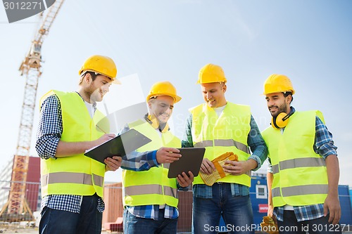 Image of group of smiling builders with tablet pc outdoors