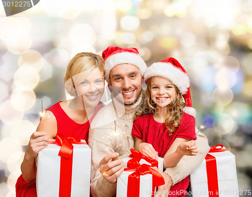 Image of happy family in santa helper hats with gift boxes