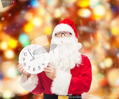 Image of man in costume of santa claus with clock