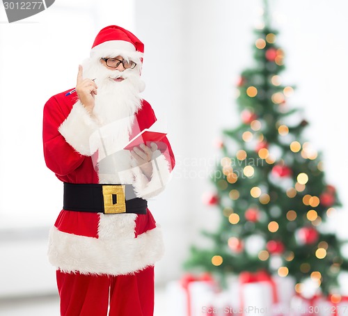 Image of man in costume of santa claus with notepad