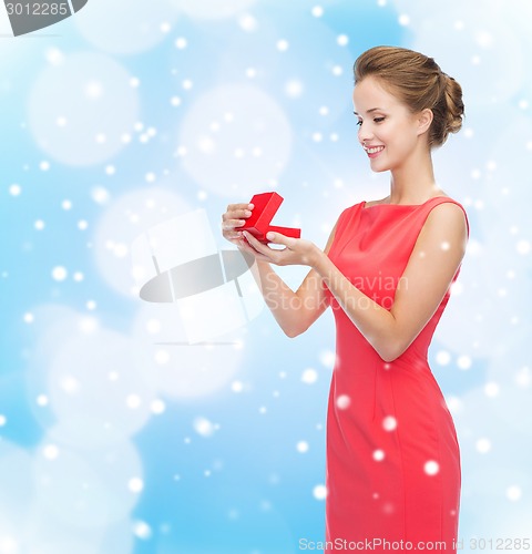 Image of smiling young woman in red dress with gift box