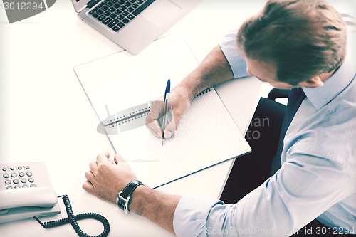 Image of businessman writing in notebook