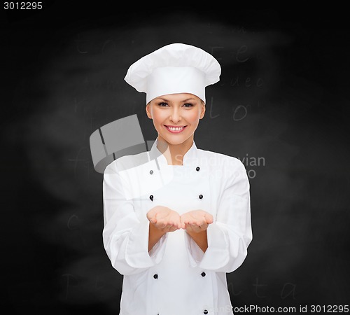 Image of smiling female chef holding something on hands