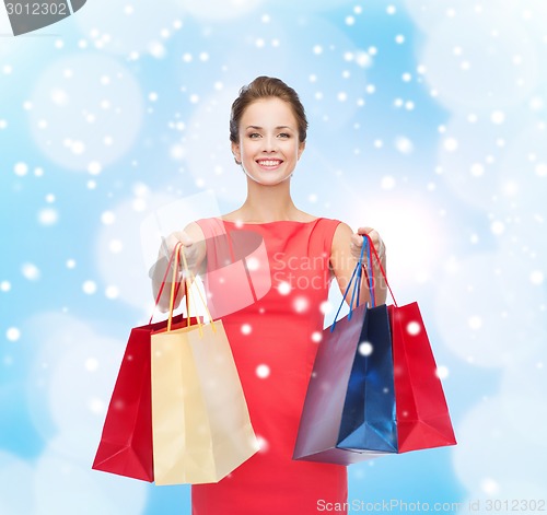 Image of smiling elegant woman in dress with shopping bags